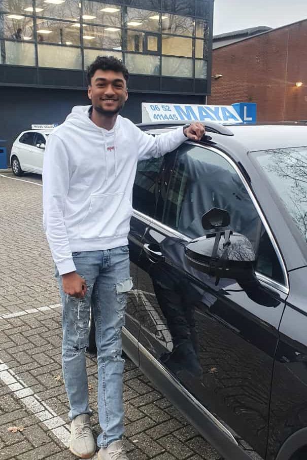 Een leerling in een witte hoodie leunt op de lesauto