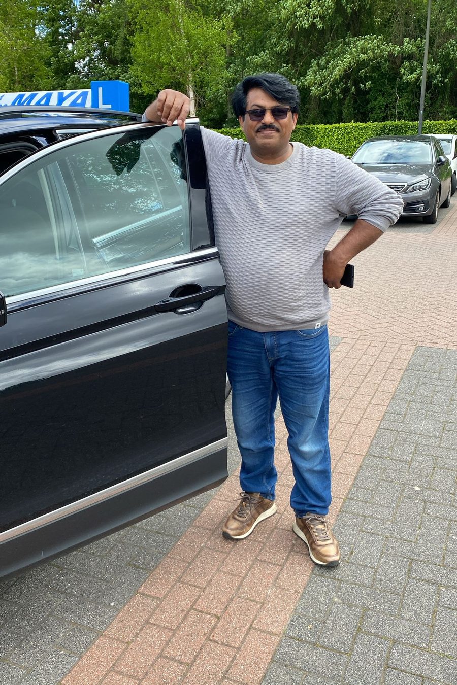 Een leerling staat bij het open portier van de lesauto